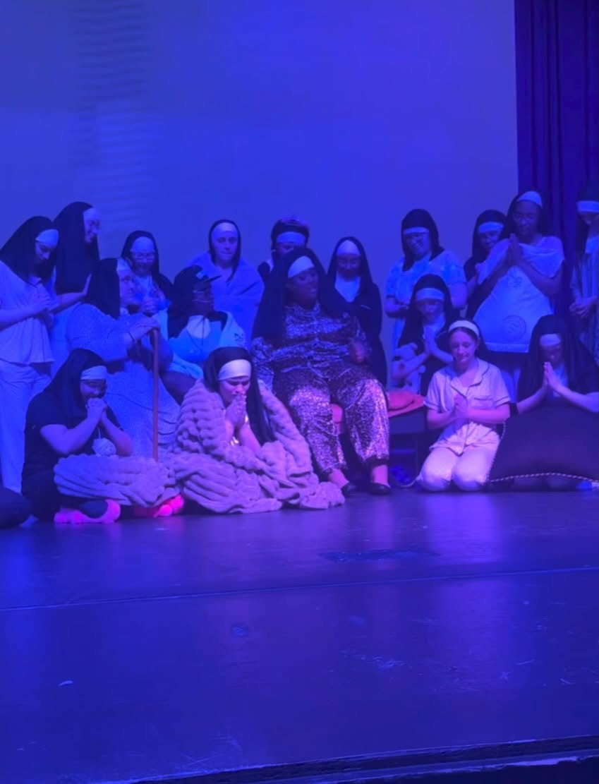 Sister Act ensemble gathered on stage under blue lighting
